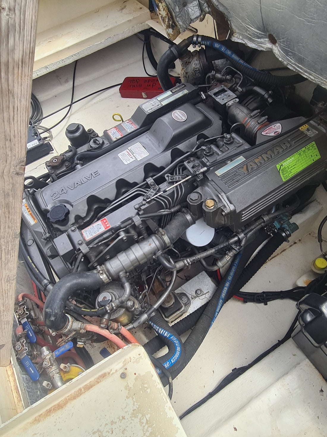 Marine diesel engine in a tight inboard bay with fuel lines and shut-off valves visible